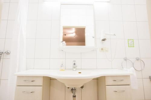 a white bathroom with a sink and a mirror at Aparthotel Wettenberg in Gießen
