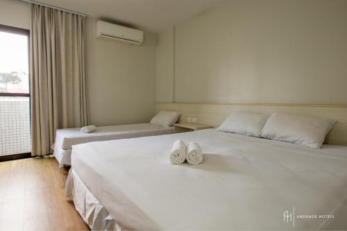 a bedroom with two beds with white shoes on them at Rede Andrade Vernon in Curitiba