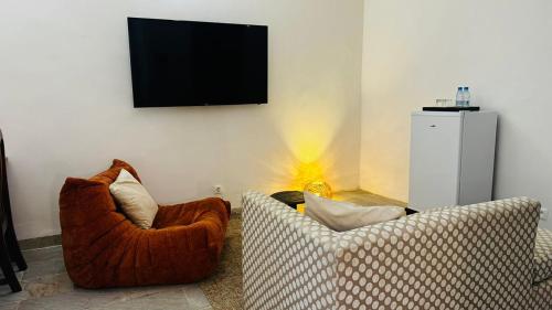 a living room with two chairs and a television on the wall at Hotel Dior in Saint-Louis