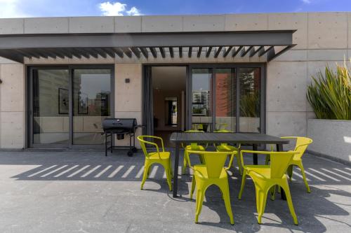 a table and yellow chairs in front of a building at Capitalia Galileo Residences in Mexico City