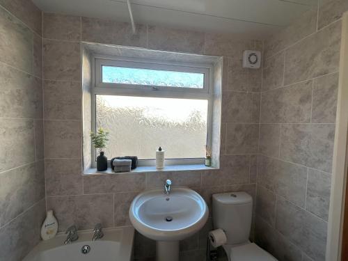 a bathroom with a sink and a toilet and a window at Bolton Terrace - 2 Bedrooms - Sleeps 4 in Workington
