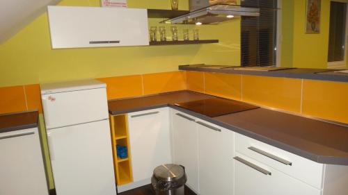a kitchen with white cabinets and orange walls at Penzión Melódia in Kanianka