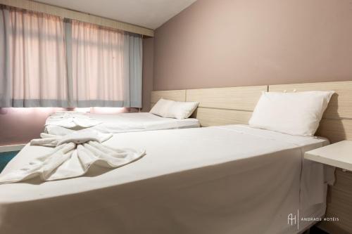two beds in a hotel room with white sheets at Rede Andrade San Martin in Curitiba