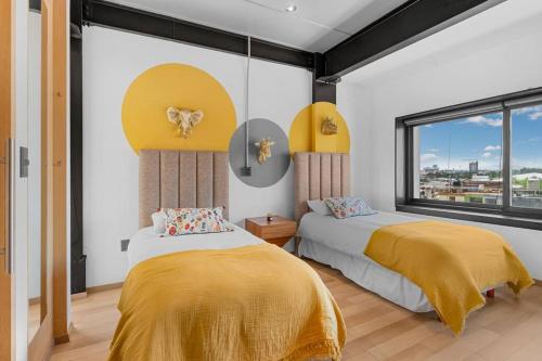two beds in a bedroom with yellow and white walls at Lujoso APARTAMENTO en Centro de Puebla in Puebla