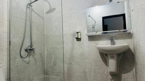 a bathroom with a shower and a sink and a glass shower door at Hotel Dior in Saint-Louis