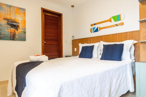 a bedroom with a large white bed with blue pillows at Pousada Portal de Búzios in Armacao dos Buzios