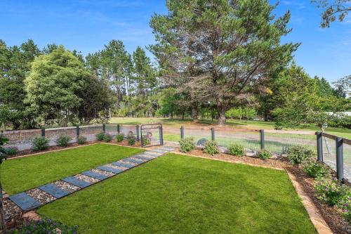 a garden with a fence and green grass at The Cottage, Colo Vale, Southern Highlands in Colo Vale