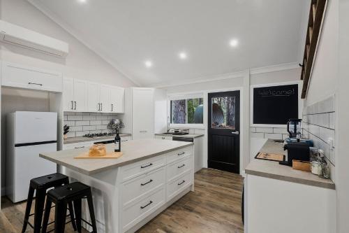 une cuisine avec des armoires blanches et un réfrigérateur blanc dans l'établissement The Cottage, Colo Vale, Southern Highlands, à Colo Vale