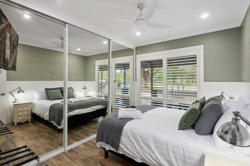 a bedroom with two beds and a mirror at The Cottage, Colo Vale, Southern Highlands in Colo Vale