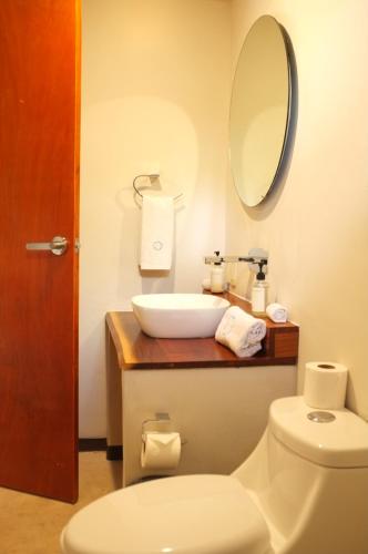a bathroom with a sink and a toilet and a mirror at Hotel Circulo Bacalar in Bacalar