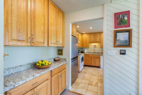 a kitchen with wooden cabinets and a bowl of fruit on the counter at Puamana 9C in Princeville