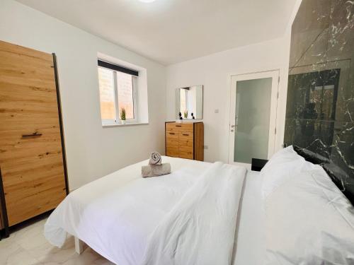a white bedroom with a large bed and a window at Beachfront Room DR in St Paul's Bay
