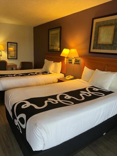 two beds in a hotel room with two lamps at La Quinta Inn by Wyndham Bossier City in Bossier City