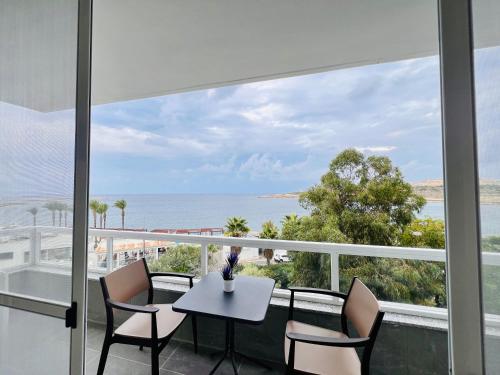 a balcony with a table and chairs and a view of the ocean at Beachfront Room DR in St Paul's Bay