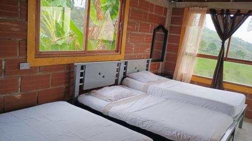 3 camas sentadas en una habitación con ventana en Cabaña Campestre San Gabriel, en Angostura