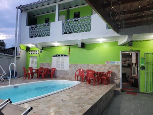 a house with a swimming pool and red chairs at Unidades 1 e 2 e 3 Pousada do Sossego Mar e Verde in Itanhaém