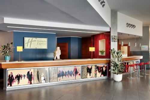 a lobby with a bar with paintings on the wall at Holiday Inn Express Milan-Malpensa Airport by IHG in Case Nuove