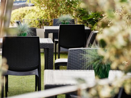 a row of tables and chairs with potted plants at Holiday Inn Express Milan-Malpensa Airport by IHG in Case Nuove