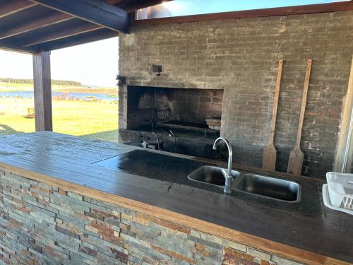 a kitchen with a sink and a brick fireplace at Chacra para 13! A 20min Punta del Este - Starlink in Maldonado
