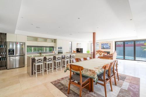 Una cocina y una sala de estar con mesa y sillas. en Clifftop Luxury with Pool, en Kiama
