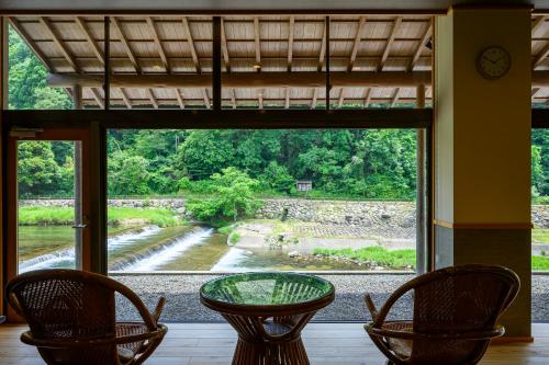 a glass table and chairs in front of a window at Ryokan Ohashi in Misasa