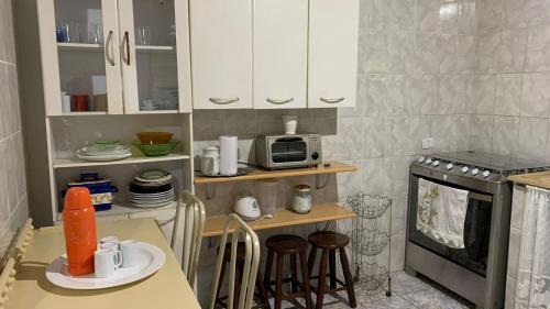 a small kitchen with a table and a microwave at Linda Chácara com Piscina Churrasqueira e Wi-FI in Mairinque