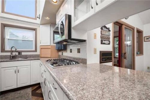 a kitchen with white cabinets and a stove top oven at 5-Bedroom Lakefront, private beach wifi AC boat & in Tobyhanna