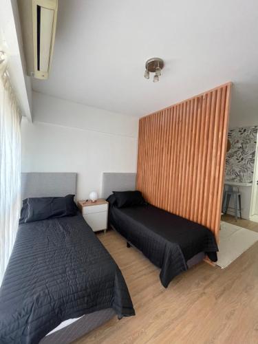 a bedroom with two beds and a wooden wall at Obelisco Haus in Buenos Aires