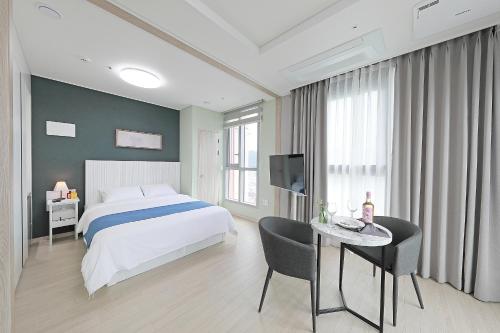 a bedroom with a bed and a desk and a television at Elmomento Sasang in Busan