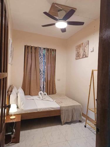 a bedroom with a bed with a ceiling fan at Bucana Beach House North El Nido in El Nido