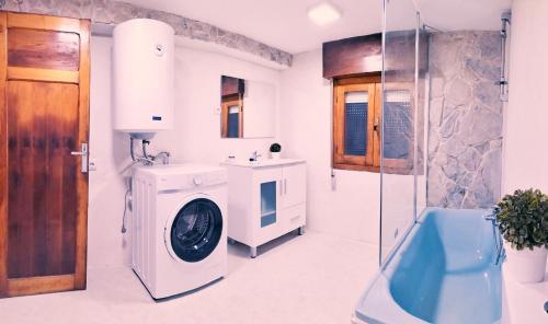 een badkamer met een wasmachine en een wastafel bij La casina Redes -Tlf 67964 nueve cero tres uno in Villamorey