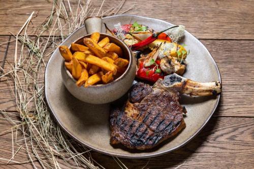 a plate with a steak and fries and a bowl of food at Salio Equisport Resort in Stryków