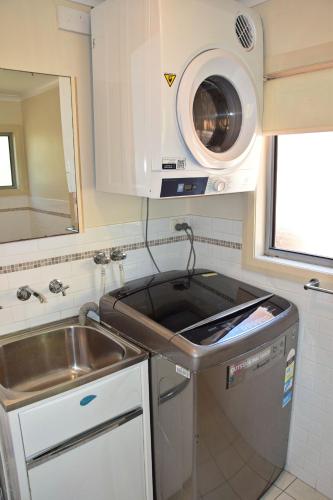 a kitchen with a sink and a washing machine at Yia Yias Place - Bring your own linen. in South West Rocks