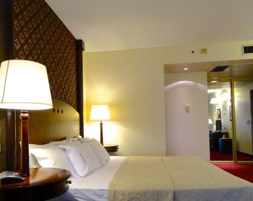 a hotel room with a bed with a lamp and a mirror at Abasto Hotel in Buenos Aires