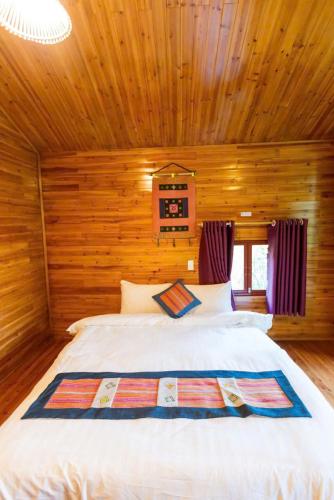 a bedroom with a white bed in a wooden room at Bac Ha Lodge Retreat in Bắc Hà
