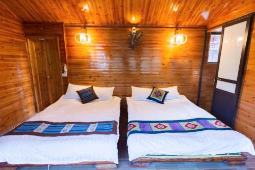 two beds in a room with wooden walls at Bac Ha Lodge Retreat in Bắc Hà