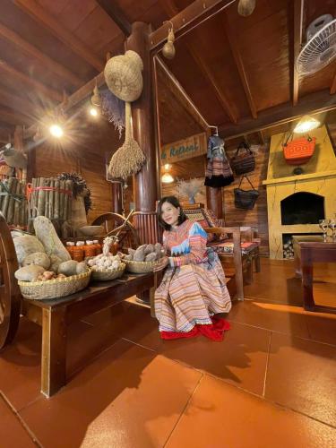 a woman is standing next to a table with food at Bac Ha Lodge Retreat in Bắc Hà