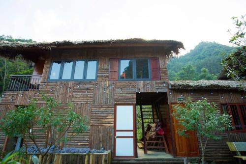 a small wooden house with a thatch roof at Bac Ha Lodge Retreat in Bắc Hà