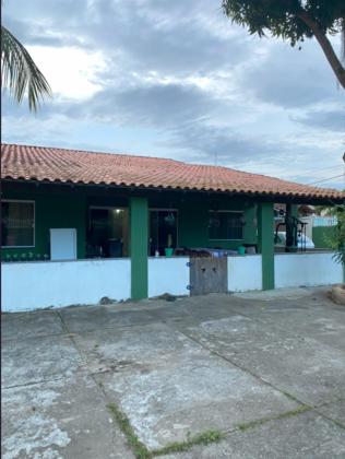 a green house with a red roof and a building at Casa perto da lagoa - Balneário São Pedro in São Pedro da Aldeia