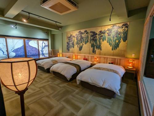 a room with four beds and a painting on the wall at Osaka Ukiyoe Ryokan in Osaka