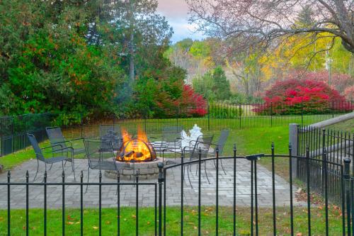 a fire pit in a park with chairs and a fence at Whitneys Inn at Black Mountain in Jackson