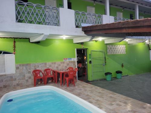 a house with a table and chairs and a swimming pool at Unidades 1 e 2 e 3 Pousada do Sossego Mar e Verde in Itanhaém