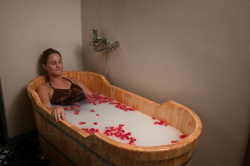 a woman sitting in a wooden tub filled with red petals at MAY DE VILLE Crown Hotel in Hanoi