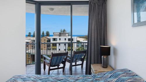 a bedroom with a bed and a balcony with a view at Centrepoint Unit 27 in Caloundra