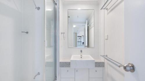 a white bathroom with a sink and a mirror at Centrepoint Unit 27 in Caloundra