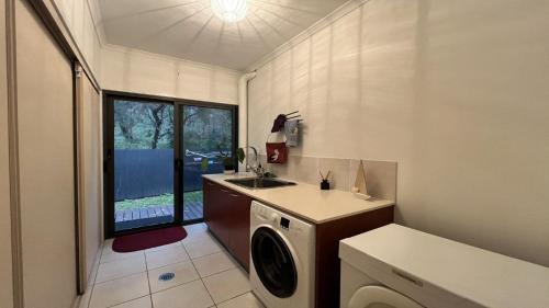 a bathroom with a sink and a washing machine at Gallery Place in Caloundra West