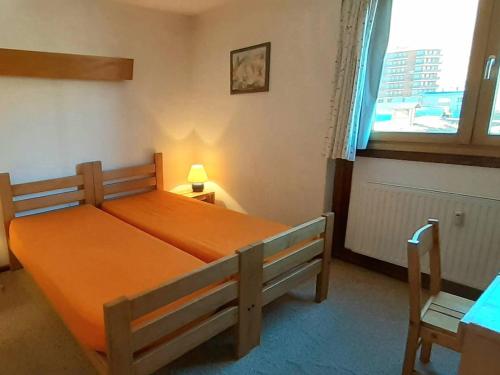 - un lit orange dans une chambre avec fenêtre dans l'établissement 3 pièces à Plagne Centre, proche commerces et Mont Blanc, animaux admis - FR-1-351-222, à La Plagne Tarentaise
