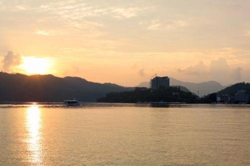 a sunset over a river with a city in the background at Grand Hilai Sun Moon Lake in Yuchi