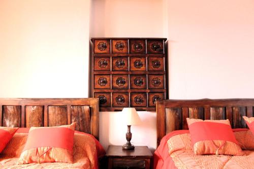 a bedroom with two beds and a table with a lamp at Apart Hotel Loma Chica Quito in Quito
