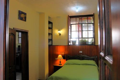 a bedroom with a green bed and a window at Apart Hotel Loma Chica Quito in Quito